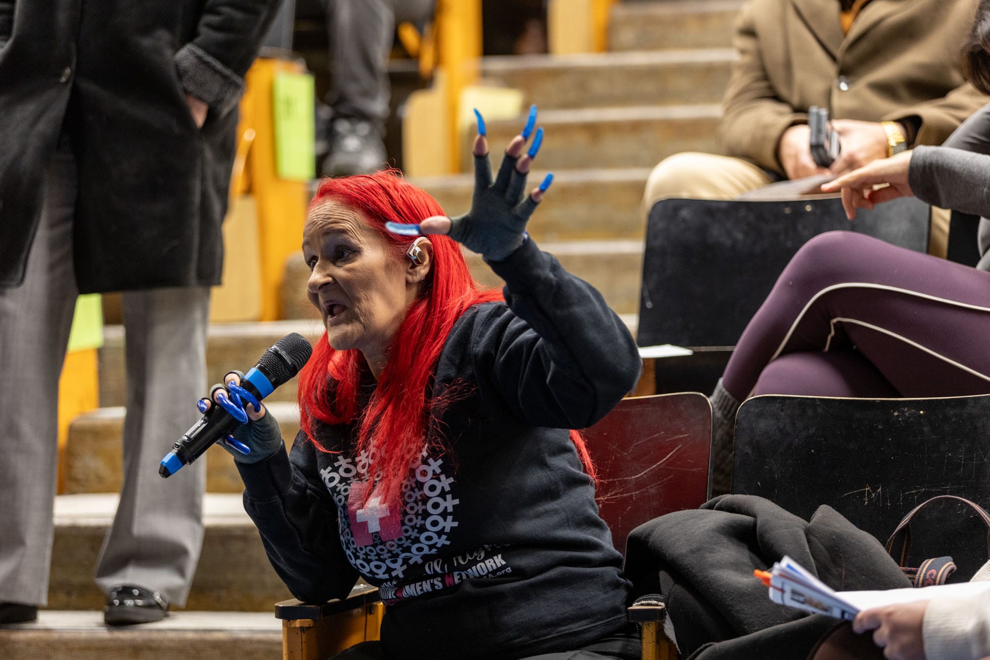 Woman with red hair speaks passionately at mobile services meeting